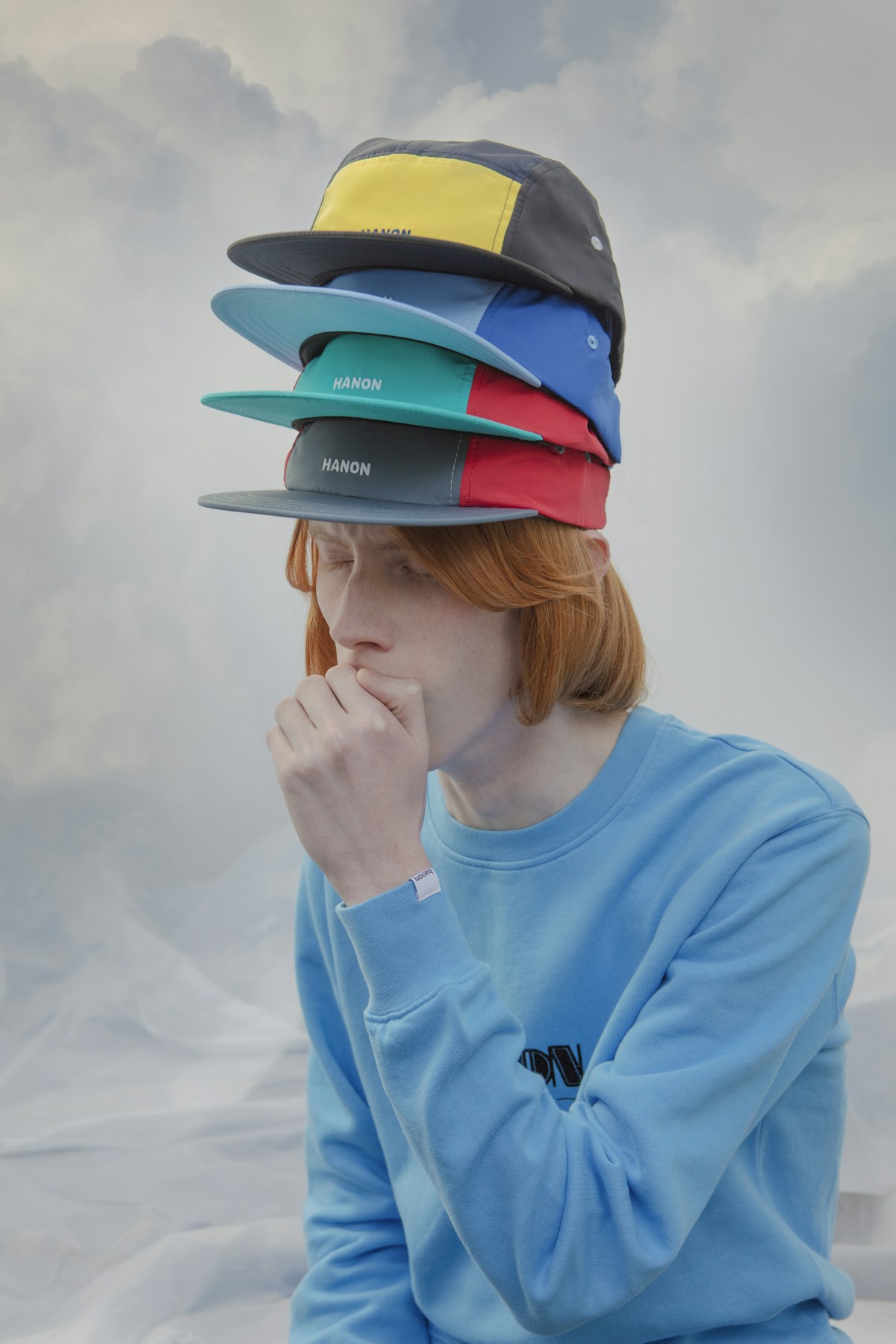 A model wearing four different coloured baseball caps on his head
